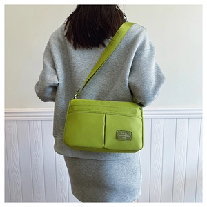 Close-up of vibrant green canvas crossbody bag featuring multi-pocket design and wide strap