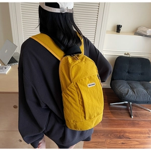 Detailed view of bright yellow lightweight nylon backpack with branded patch being worn