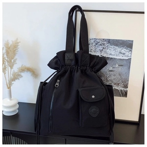 Close-up of black canvas bucket bag with drawstring closure and functional pockets