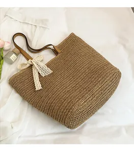 Close-up of woven straw tote bag featuring a white lace bow and brown leather handle