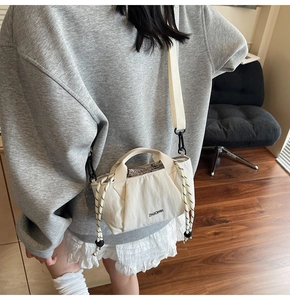 Detail of white nylon bucket bag with drawstring closure and woven rope accents