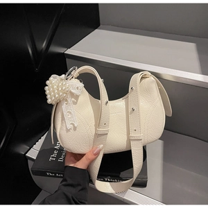 Detail of cream pleated baguette bag with pearl grape charm and lace bow decor