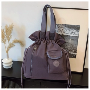 Detail of purple pleated drawstring bucket bag with metal zipper and round logo pocket