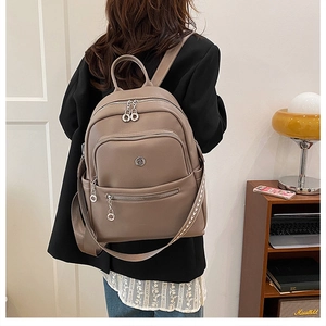 Detail view of khaki PU leather backpack showing multi-zipper pockets and silver hardware