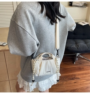 Rear view of a model wearing a cream drawstring bucket bag with the ZHUOFAN logo