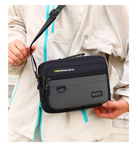 Detail of man wearing black and grey oxford crossbody bag with multiple zip pockets