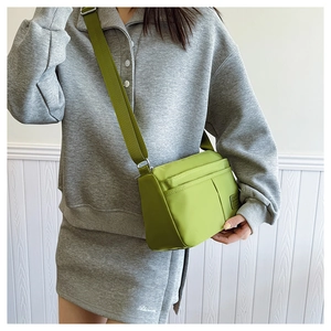 Detail of avocado green nylon crossbody bag with multi-pocket design and wide strap