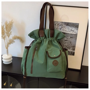 Detail of green canvas travel bag featuring drawstring closure and functional front pockets