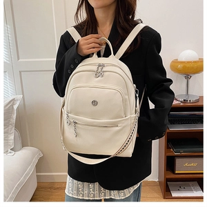 Close-up of minimalist cream leather backpack featuring textured finish and metal zipper