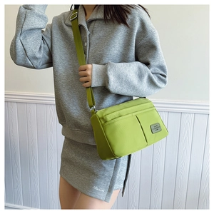 Detail of lime green canvas messenger bag featuring a wide adjustable strap and utility pockets