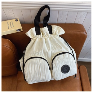 Detail of white nylon backpack featuring pleated texture and round brand logo patch