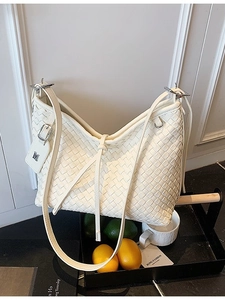 White woven Hobo shoulder bag with silver M charm and adjustable strap on a tray
