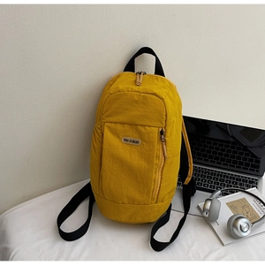 Close-up of bright yellow nylon backpack with a vertical zipper pocket on a white desk