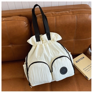 Detail of off-white drawstring backpack with dual zip pockets and black logo on sofa