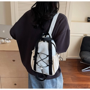 Detail of a white functional mini backpack featuring black straps and drawstring design