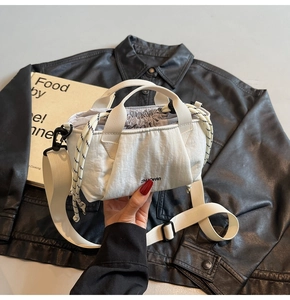 Close-up of white drawstring bucket bag with branded strap and textured nylon fabric