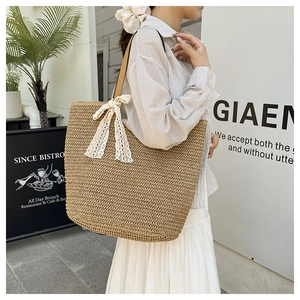 Detailed close-up of woven straw tote bag with lace bow decoration and leather handles