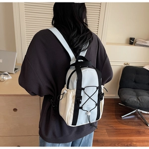Detail view of a light blue and beige two-tone backpack with adjustable side pockets