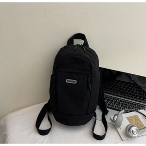 Minimalist black backpack with metal brand tag placed on a desk with a laptop