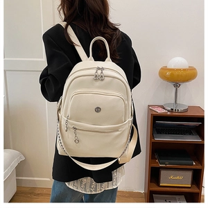 Detailed close-up of a cream faux leather backpack with litchi texture and metal zippers