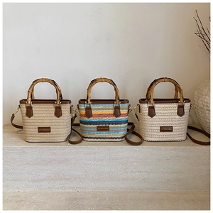 Detail of bohemian woven straw bags with bamboo handles and leather straps