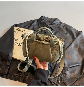 Detail of olive green nylon bucket bag with woven drawstring and textured fabric