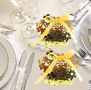 Detail of golden laser-cut floral candy box with silk bow on elegant dinner table setup