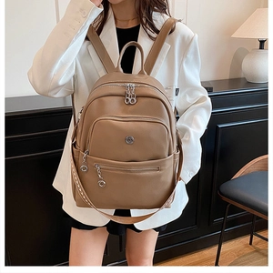 Detail view of brown faux leather backpack showing multiple zipper compartments and texture