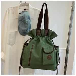 Detail of forest green canvas bucket bag with drawstring closure and brown straps