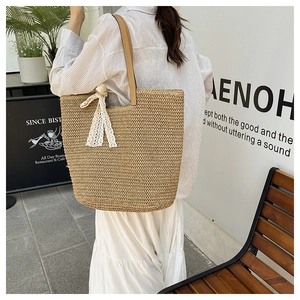 Detail of hand-woven straw tote with elegant white lace bow and brown leather shoulder strap