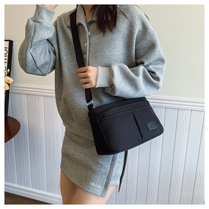 Detail view of a black nylon crossbody bag with multi-pockets and adjustable strap