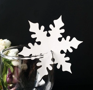 Intricate white snowflake placeholder card made of thick paper on a glass rim for parties