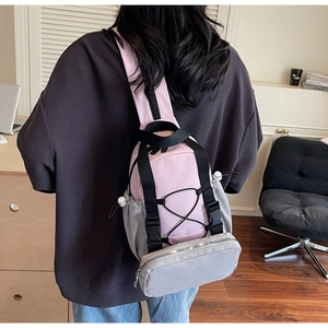 Detail of pink and gray nylon functional chest bag with adjustable straps and drawstring