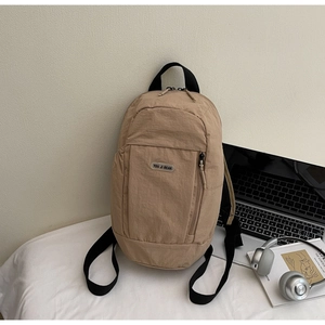 Detail of khaki nylon backpack featuring front vertical zipper and branded brand label