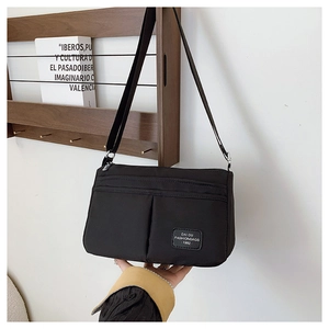 Detail of black crossbody bag featuring dual front pockets and adjustable strap for daily use