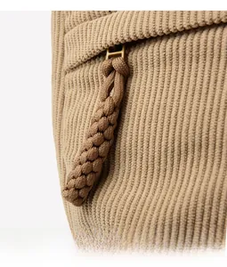 Detailed close-up of khaki corduroy fabric and woven zipper pull on a hobo bag