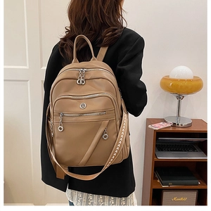 Dettaglio zaino in pelle marrone con spallacci in tessuto e cerniere metalliche silver