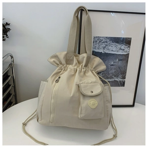 Detail of cream drawstring bucket bag with vertical zippers and pocket texture