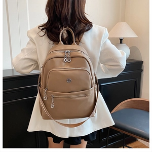 Detail view of a brown leather backpack on a model in a minimalist indoor setting