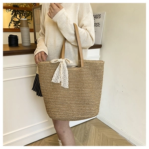 Close-up of a woven straw tote bag with lace bow detail and brown leather handle