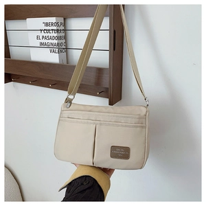Close-up of beige nylon crossbody bag with dual functional pockets and leather logo