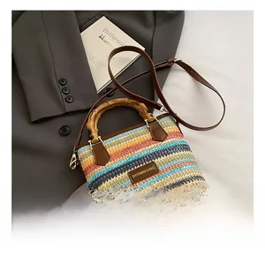 Close-up of rainbow straw bag featuring bamboo handle and leather logo detail