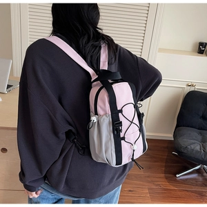 Pink and grey techwear mini backpack shown on model in a modern office setting