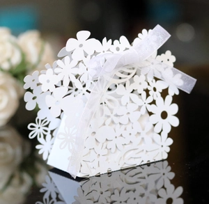 Detailed laser-cut floral pattern and white satin ribbon on wedding favor box