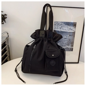 Detail of black pleated bucket bag with drawstring closure and front zipper pocket