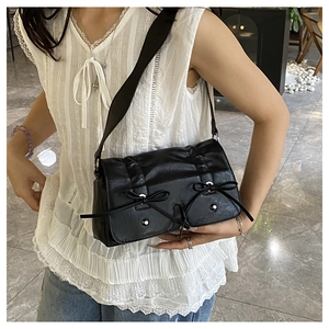 Detail of black bow shoulder bag featuring pleated faux leather and silver metal studs