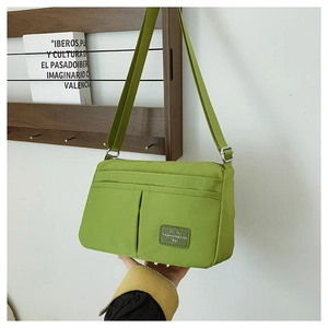 Detail of lime green nylon crossbody bag with vintage logo patch and adjustable strap