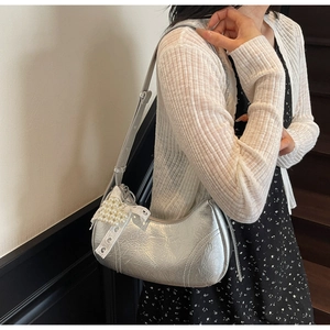 Detail of silver metallic crescent bag with wrinkled texture and pearl lace bow charm