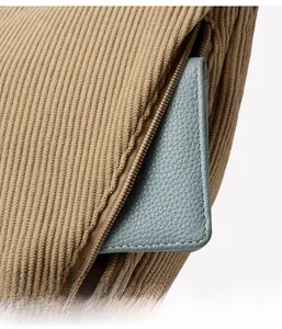 Detailed view of corduroy bag side zipper pocket with light blue leather wallet inside