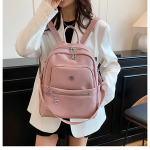 Detail of pink leather backpack featuring silver zippers and stylish metal charms